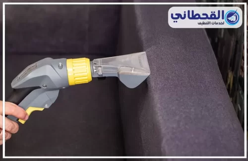 افضل شركة تنظيف مجالس بالرياض | 0548145142 | شركة القحطاني شخص يقوم بتنظيف الأريكة بالمكنسة الكهربائية، ويوضح خدمات التنظيف.
