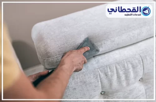 تنظيف ستائر المجالس بالرياض | 0548145142 | شركة القحطاني رجل يستخدم قطعة قماش بيضاء لتنظيف الأريكة، ويعرض خدمات التنظيف الاحترافية في الرياض.