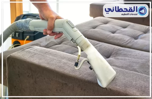 تنظيف المجالس القماش بالرياض | 0548145142 | شركة القحطاني شخص يستخدم المكنسة الكهربائية لتنظيف الأريكة، ويعرض تقنيات فعالة لتنظيف المفروشات.