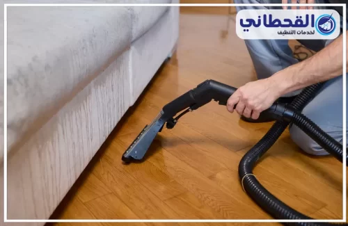 تنظيف فرش البيت شمال الرياض 0548145142 القحطاني فني شركة نظافة شمال الرياض أثناء تنظيف الأريكة باستخدام جهاز مكنسة كهربائية لإزالة الأوساخ.