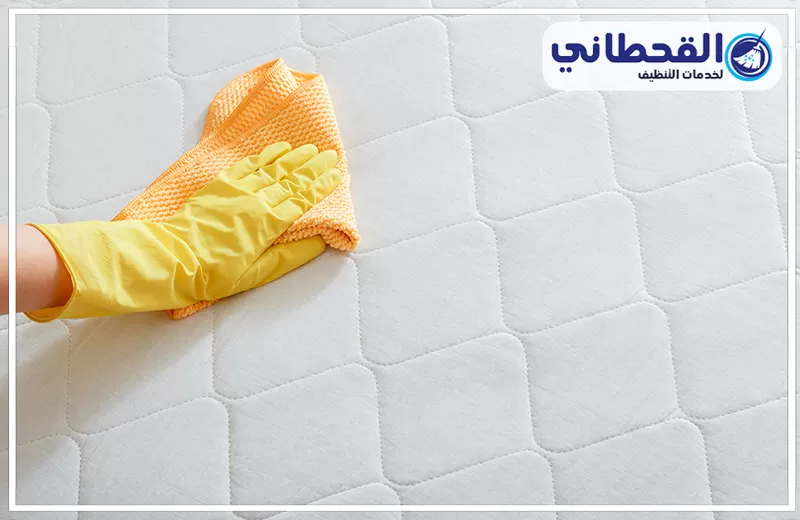تنظيف مراتب سرير في المنزل بسيهات 0548145142 القحطاني فني يرتدي قفازات يقوم بمسح مرتبة بيضاء لتنظيف مراتب سرير في المنزل بسيهات.