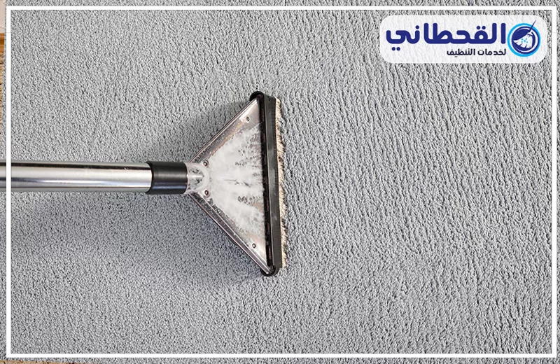 شركة تنظيف سجاد بسيهات 0548145142 القحطاني تنظيف سجاد رمادي بجهاز مخصص لإزالة الأوساخ والرواسب، مع ظهور شعار القحطاني لخدمات التنظيف أعلى الصورة.