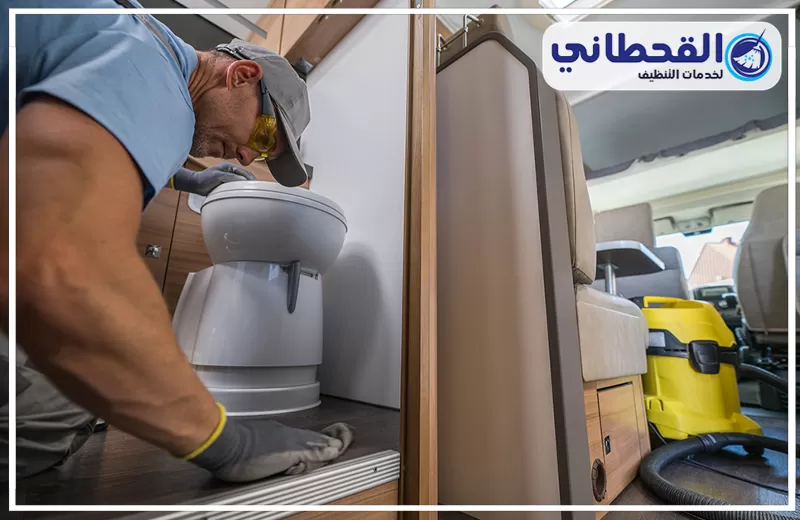 عامل ينظف أرضية كرفان من الداخل، مع مسح الطاولات والمقاعد وإزالة الغبار من الزوايا والمساحات الضيقة.