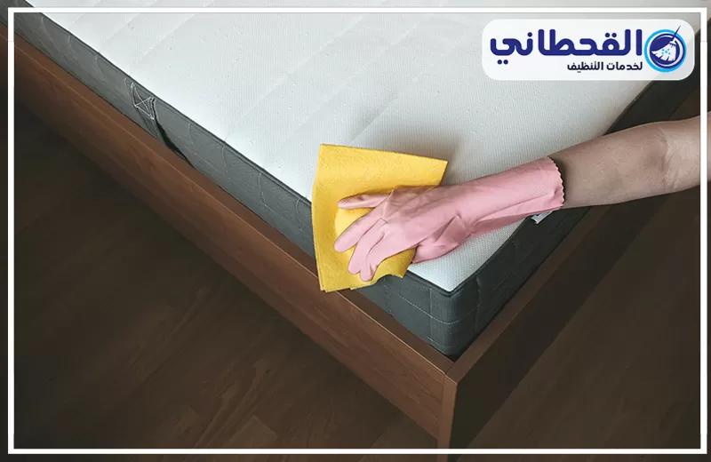 تنظيف المراتب الطبية بالبخر 0548145142 شركة القحطاني تنظيف مرتبة سرير يدويًا باستخدام قطعة قماش، مع ظهور شعار القحطاني لخدمات التنظيف.