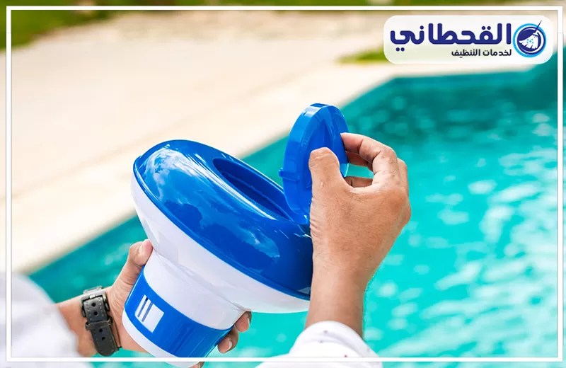 غسيل وتطهير المسابح بالخبر 0548145142 شركة القحطاني إضافة مواد تعقيم وتنقية للمسبح باستخدام أداة مخصصة، مع ظهور المياه الصافية في الخلفية.