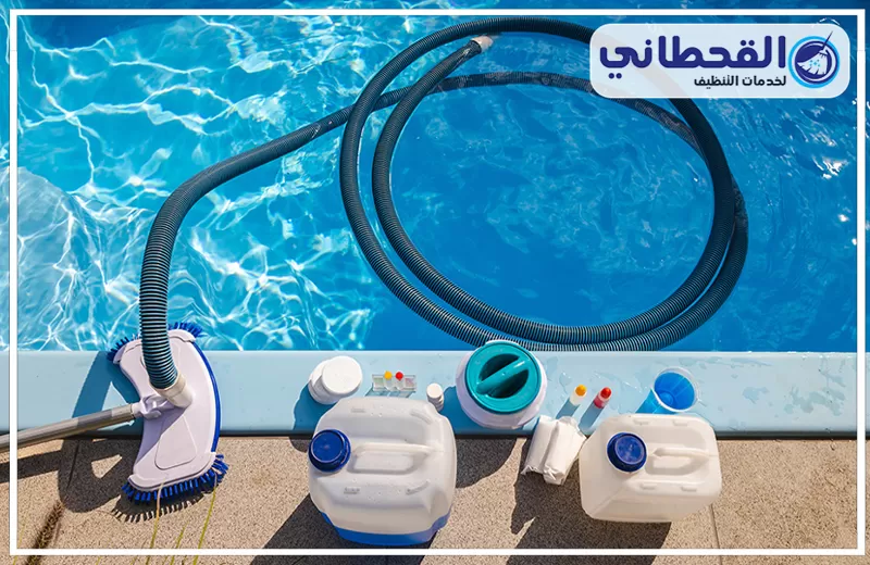 صيانة مسابح بالظهران 0548145142 شركة القحطاني. أدوات تنظيف مسبح على الحافة مع خرطوم أزرق ملتف داخل المياه وفرشاة تنظيف وعبوات مواد تنظيف.