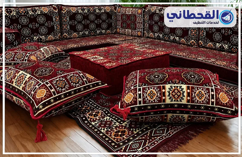 غسيل مجالس بالظهران 0548145142 شركة القحطاني. مجلس عربي أرضي مزخرف باللونين الأحمر والأسود مع وسائد كبيرة وسجادة متناسقة وشعار القحطاني للتنظيف.