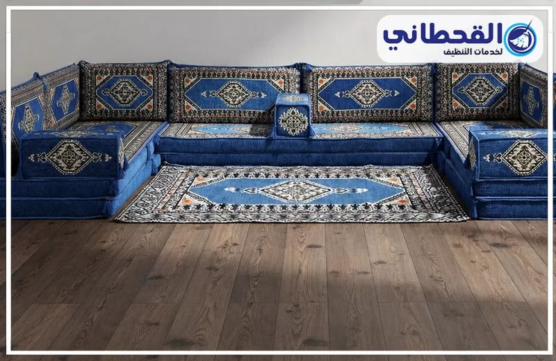 تنظيف مجالس مخمل بالظهران 0548145142 شركة القحطاني. مجلس عربي أزرق مزخرف مع سجادة متناسقة وأرضية خشبية وشعار القحطاني للتنظيف.